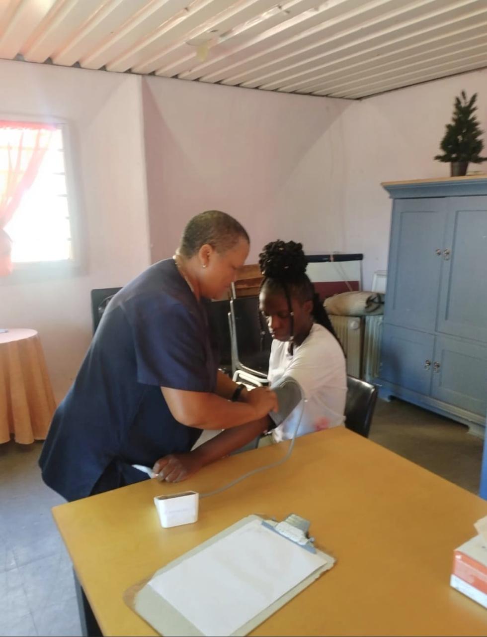An IPI professional nurse taking a young patient's blood pressure during a home-based care visit in Cape Town